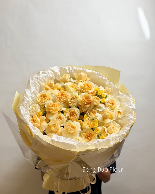 Bó hoa hồng vàng kem xếp tròn, gói giấy kem.