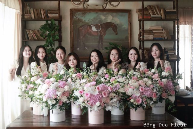 Cả nhóm học viên đứng cạnh những bình hoa vừa tự tay cắm trong buổi workshop của Bông Dua Fleur.